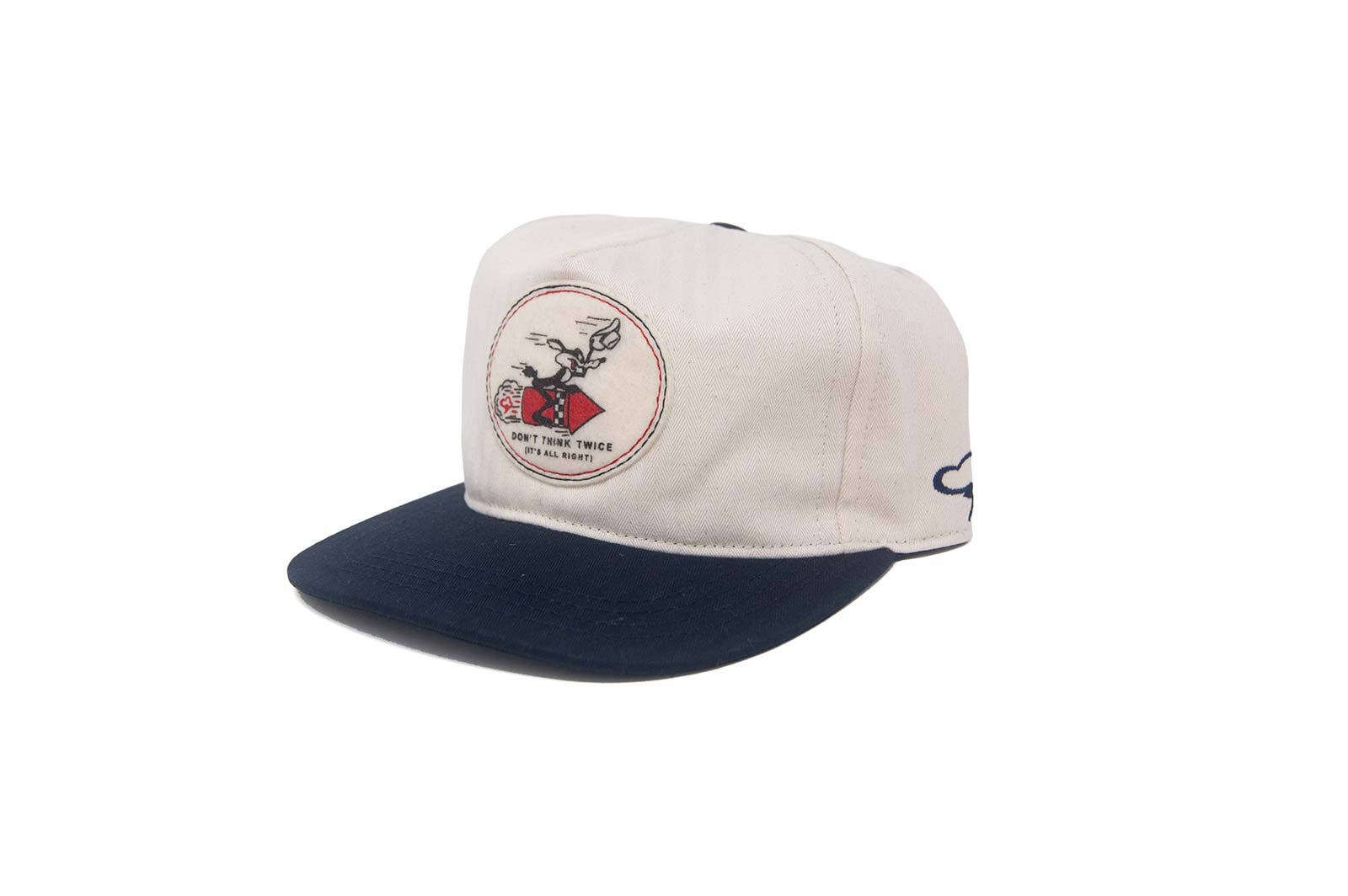 The Ampal Creative - Don't Think Twice Snapback in navy features a front patch with a person riding a fish and the text “Don’t Think Twice, It’s All Right.” This cap has a curved brim and classic design.