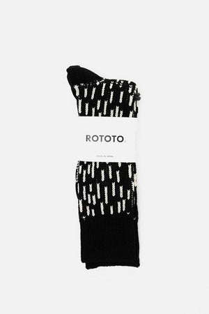 A pair of RoToTo Rain Drop Socks in Black Ivory, featuring a white dashed pattern, neatly folded with a branded label. Made in Japan by RoToTo and displayed against a plain white background.