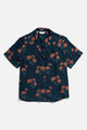 The Mila Cropped Shirt by Bridge & Burn features a relaxed fit, notched collar, and short sleeves. It’s a button-up modal shirt with a dark navy base and all-over orange and green wildflower print.