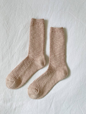 A pair of Le Bon Shoppe - Cottage Socks in Peachy Keen, chunky knit and beige, laid flat side by side on a white fabric background.