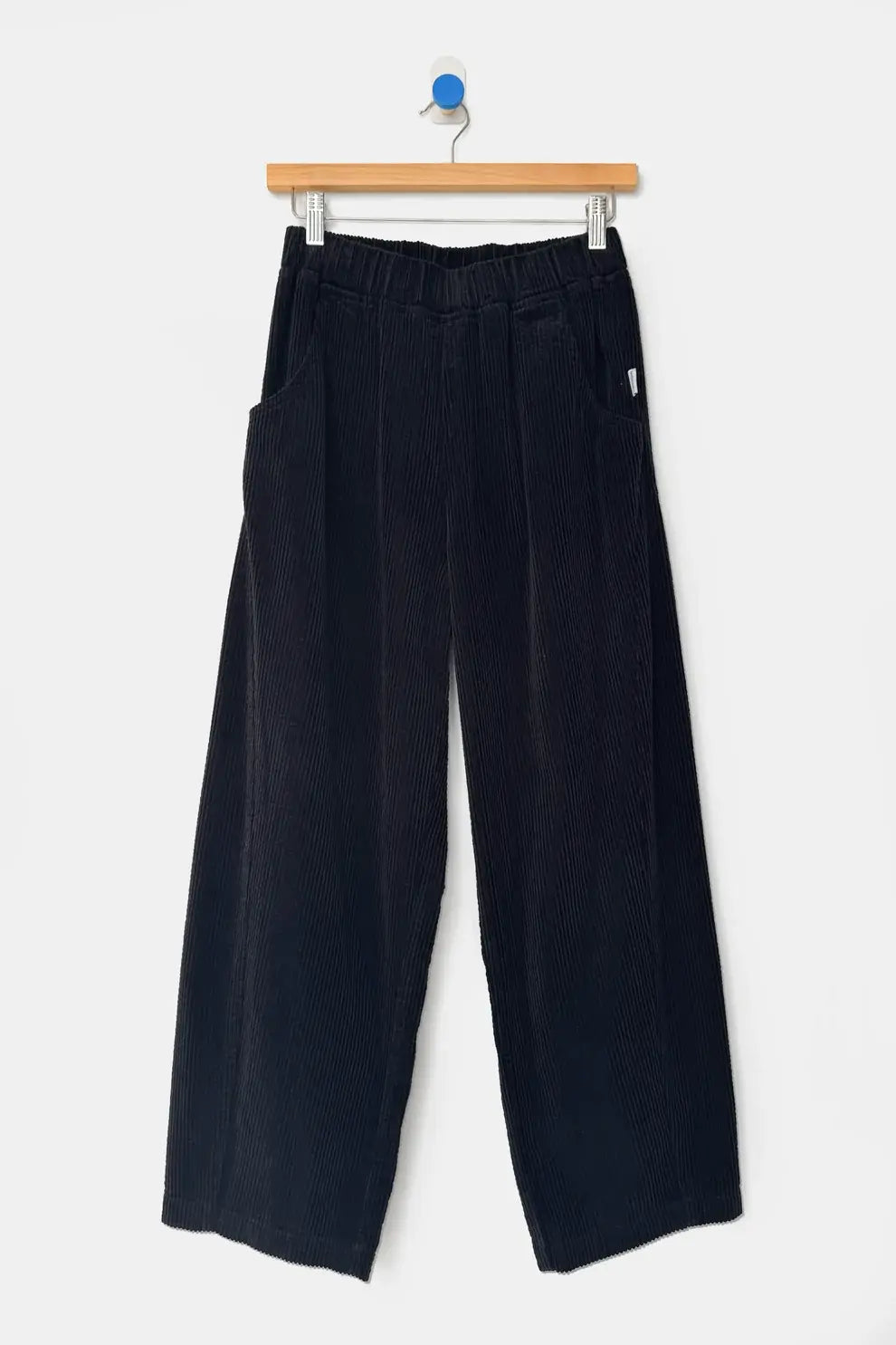 Le Bon Shoppe Soft Corduroy Arc Pant in black, featuring a wide-leg cropped fit and elastic high waist, hanging on a wooden hanger.