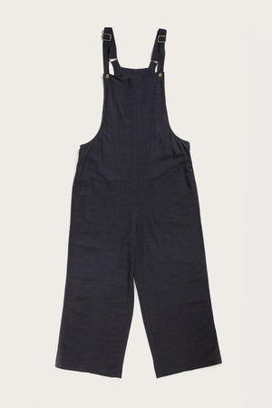 The Bridge & Burn Edie Overall in Navy is a loose-fit, wide-leg overall made from a soft linen-cotton blend with adjustable straps, a high bib front, and two front patch pockets, shown laid flat on a white background.
