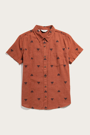 The Lana Shirt / Rust Fil-Coupé Pyramids by Bridge & Burn is a sustainable, short sleeve button-up made from soft organic cotton. It features a collar, front pocket, black geometric fil coupé jacquard patterns, and is shown on a white background.