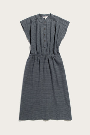 The Lorane Dress by Bridge & Burn features a sleeveless, knee-length design in navy grid cotton with a gathered waist, button-up front, and collarless round neckline—ideal for everyday casual wear.