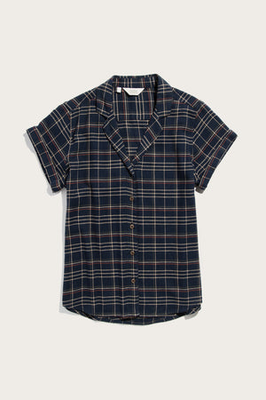 The Bridge & Burn Innes Shirt in Dusk Herringbone Plaid is a relaxed fit, short-sleeve button-up made from recycled cotton, featuring a navy and white plaid, notched collar, and cuffed sleeves. Laid flat on a white background.