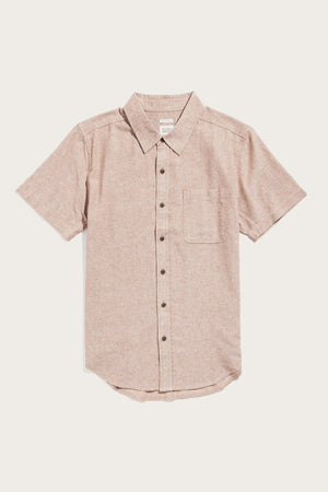 The Malcolm Shirt in Rust Chambray by Bridge & Burn is a short sleeve button-up made from recycled cotton, with a front chest pocket, spread collar, and brown buttons, shown flat on a white background.