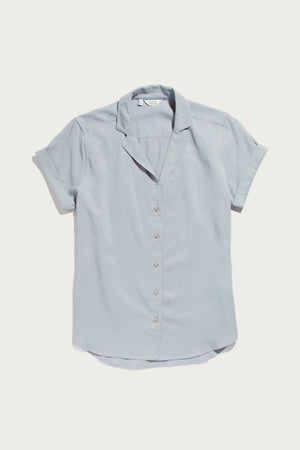 The Bridge & Burn Innes Shirt in light blue features short sleeves with cuffs, a lapel collar, and a slightly curved hem, shown flat on a white background.