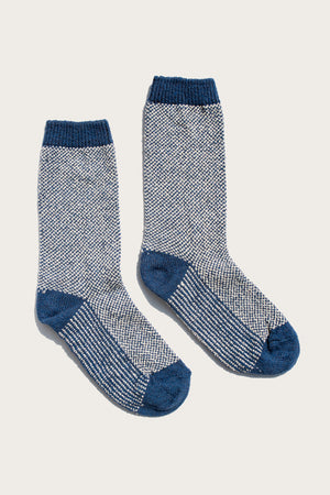 The Bridge & Burn Helix Sock / Navy features a cozy, textured blue and white speckled design with solid navy heels, toes, and cuffs. These crew-length socks are shown laid flat on a light background.