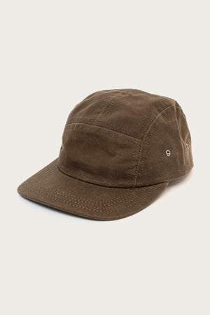 The Bridge & Burn Camper Waxed 5 Panel Cap in Umber features a brown waxed finish, curved brim, metal side eyelets, and visible stitching, shown against a plain light background.