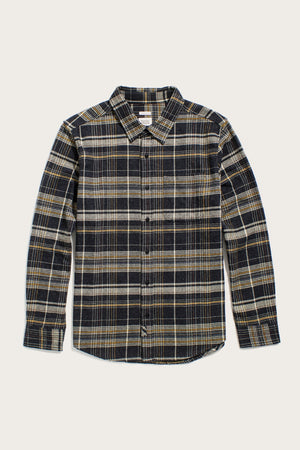 The Bridge & Burn Larson Shirt in Volcanic Plaid is a brushed flannel button-up with a classic fit, black/yellow/white tones, collar, and single chest pocket. Made from recycled cotton, shown laid flat on a white background.