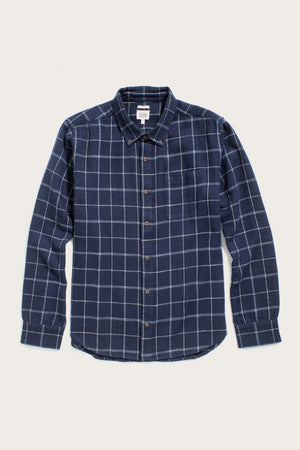 The Bridge & Burn Sutton Slim Shirt in Moonrise Windowpane is an organic cotton, long-sleeve button-up with a navy background, white check pattern, collar, and chest pocket, displayed flat on a white surface for a minimalist look.