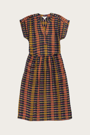 The Bridge & Burn Ira Dress in Alpenglow Stripe is a knee-length pullover with dolman sleeves and a V-neck, featuring eco-friendly viscose in orange, black, yellow, and white stripes, shown laid flat on a light background.