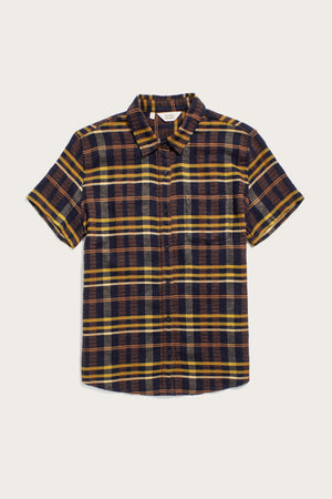 The Bridge & Burn Lana Shirt in Desert Dawn Plaid features a relaxed fit, short sleeves, collar, front chest pocket, and is crafted from organic cotton in yellow, brown, and navy blue plaid. Shown laid flat on a white background.