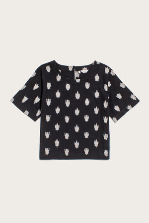 The Bridge & Burn Leona Shirt in Eclipse Ikat features short sleeves, a boxy fit, round neckline, and an evenly spaced white abstract pattern on black fabric. Displayed flat on a white background.