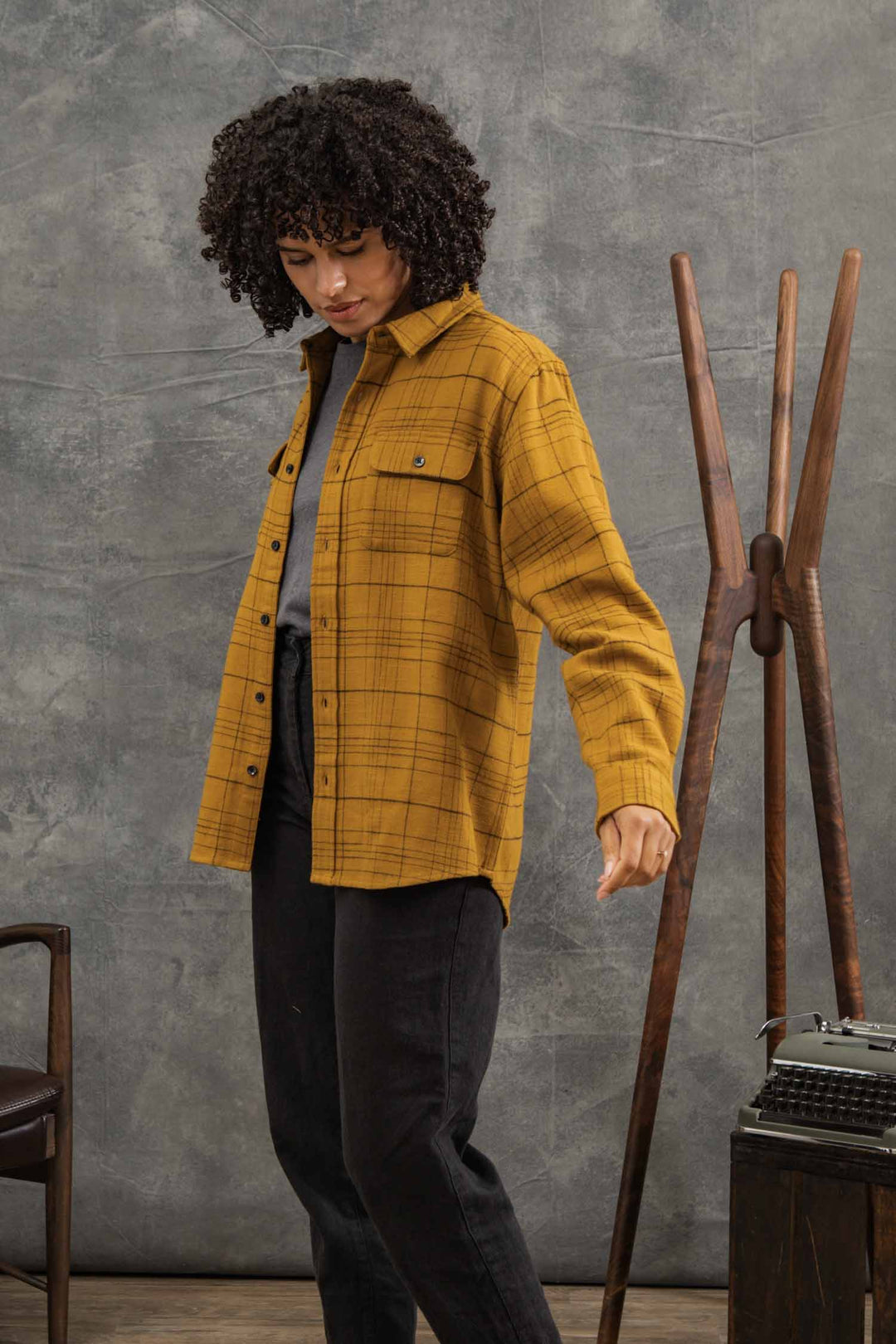 A person wearing a mustard yellow and black plaid Bridge & Burn Lenon Shirt / Golden Horizon Plaid over a grey t-shirt and black pants.