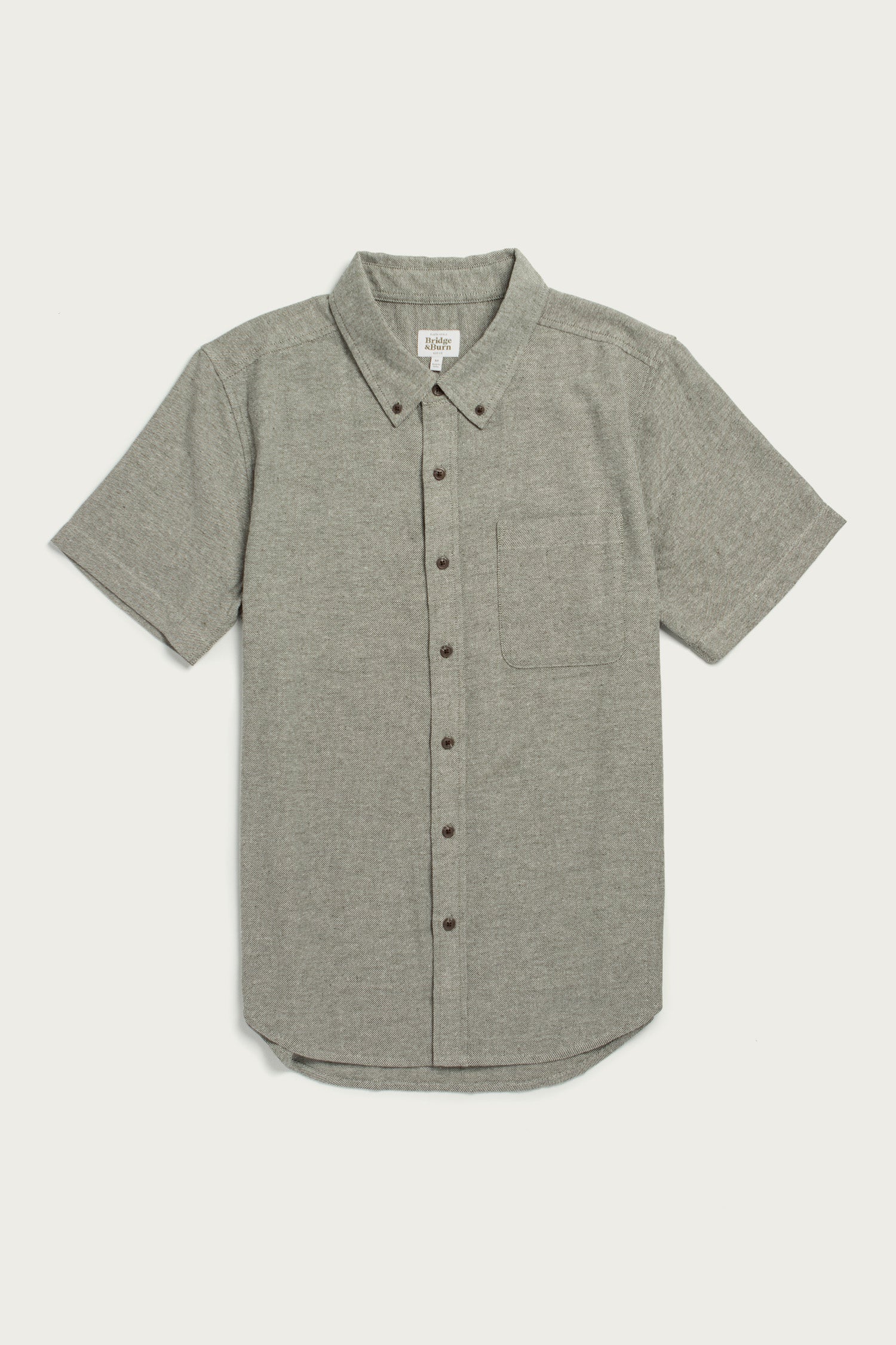 The Bridge & Burn Bryce Shirt in Olive Twill is a short sleeve, button-down men’s shirt with a left chest pocket, made from recycled cotton for sustainability, shown laid flat on a white background.