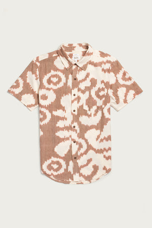 The Bridge & Burn Harbor Slim Shirt / Pop Leaf is a short-sleeve summerweight cotton button-up with a brown and white abstract, ikat-inspired pattern, shown laid flat on a white background.