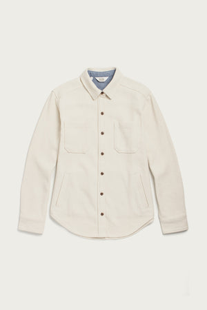 The Bridge & Burn Dawson Overshirt in Ivory Twill is a cream-colored, recycled cotton button-up with brown buttons, a light blue inner collar lining, two chest pockets, side pockets, and long sleeves. Laid flat on a white background.