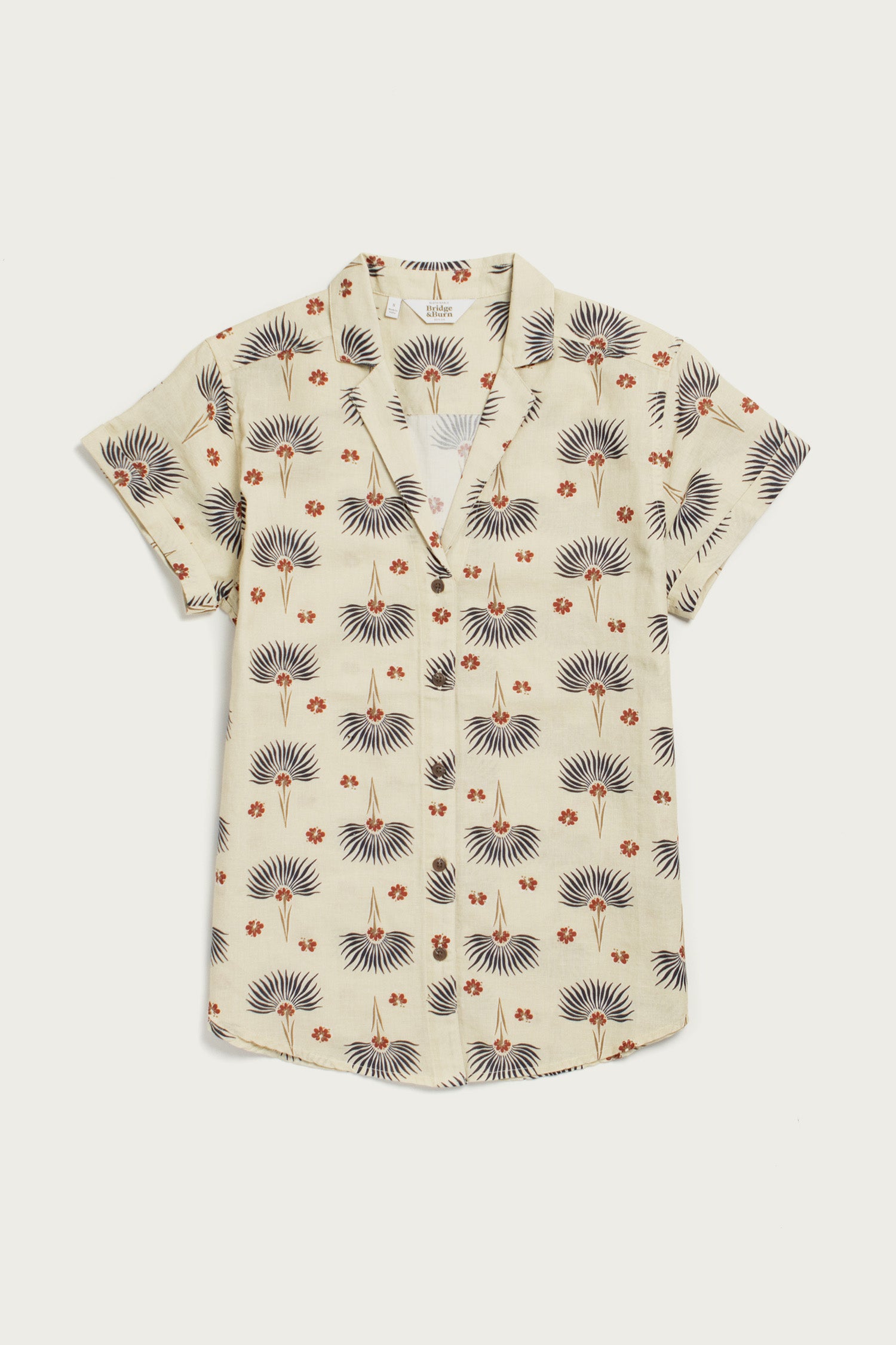 The Bridge & Burn Innes Shirt / Aloha Floral is a short-sleeved, cream linen-cotton button-up with a collar, featuring dark blue fan-shaped leaves and small orange flowers in a relaxed fit.