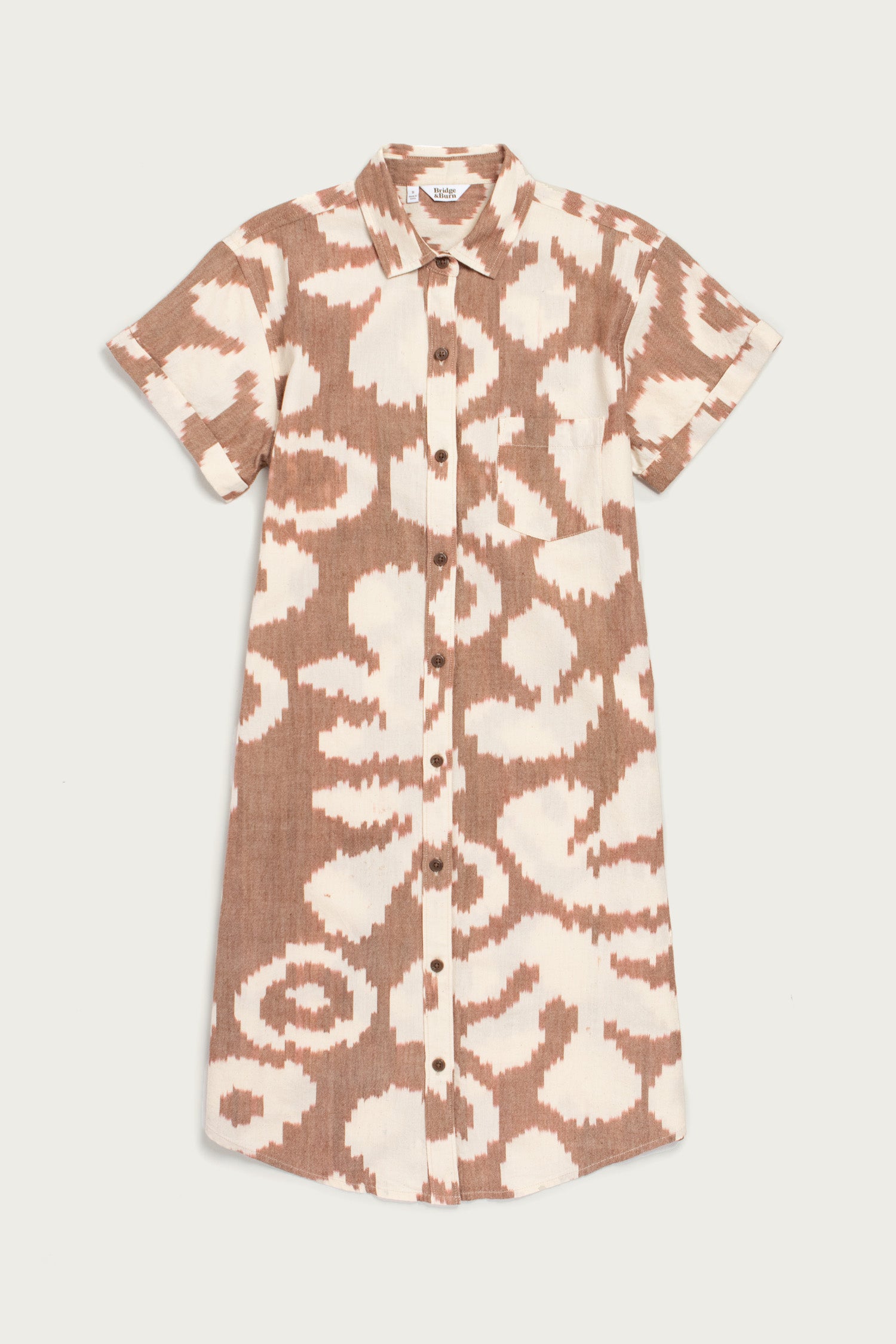 The Loren Shirt Dress by Bridge & Burn features short sleeves, a knee-length cut, collar, button front closure, and a light brown and white abstract Pop Leaf print. Made from 100% cotton.