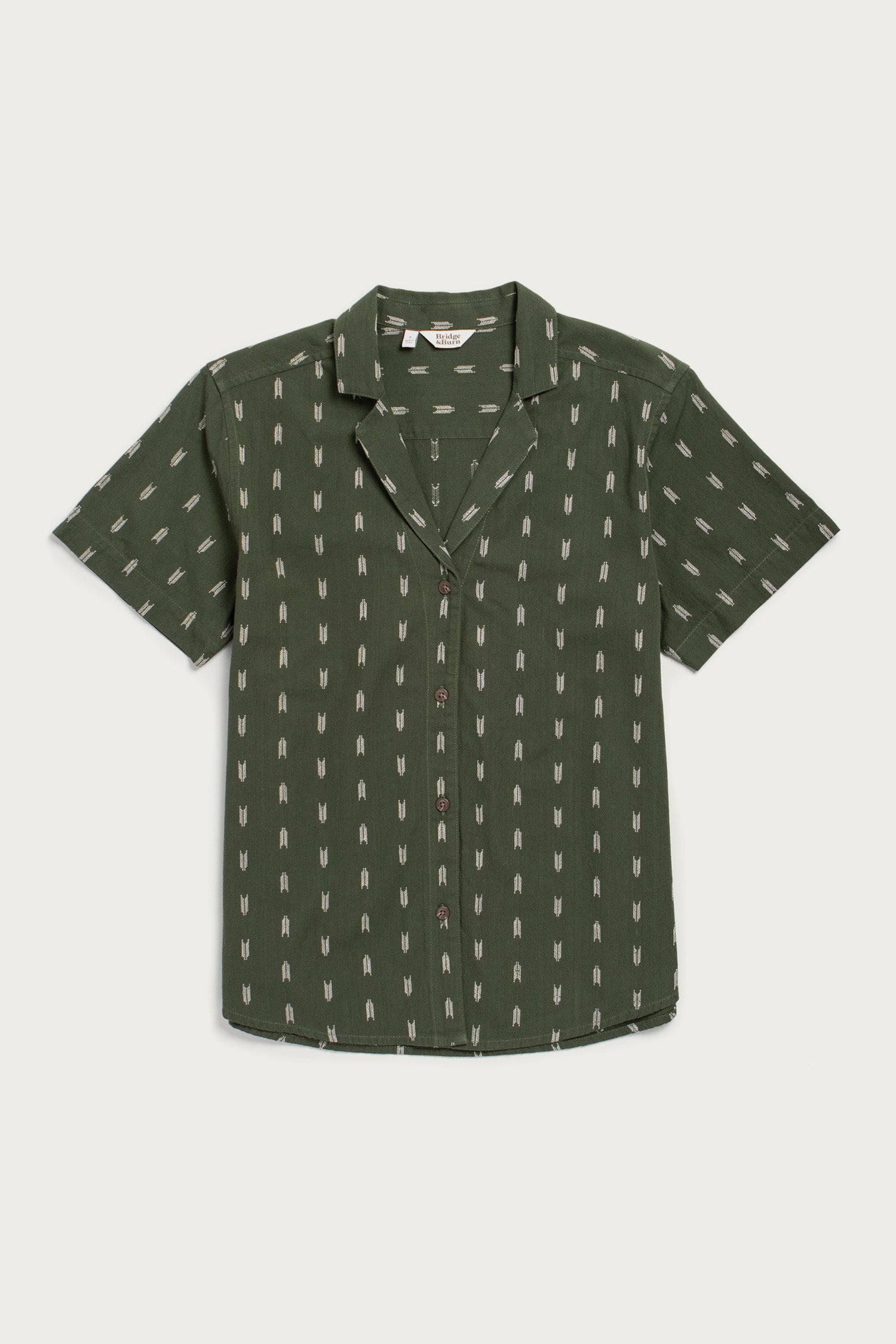 The Bridge & Burn Wren Shirt in Thyme Arrows is a relaxed-fit, lightweight cotton short-sleeve button-up with an open collar and white dash pattern, shown laid flat on a white background.