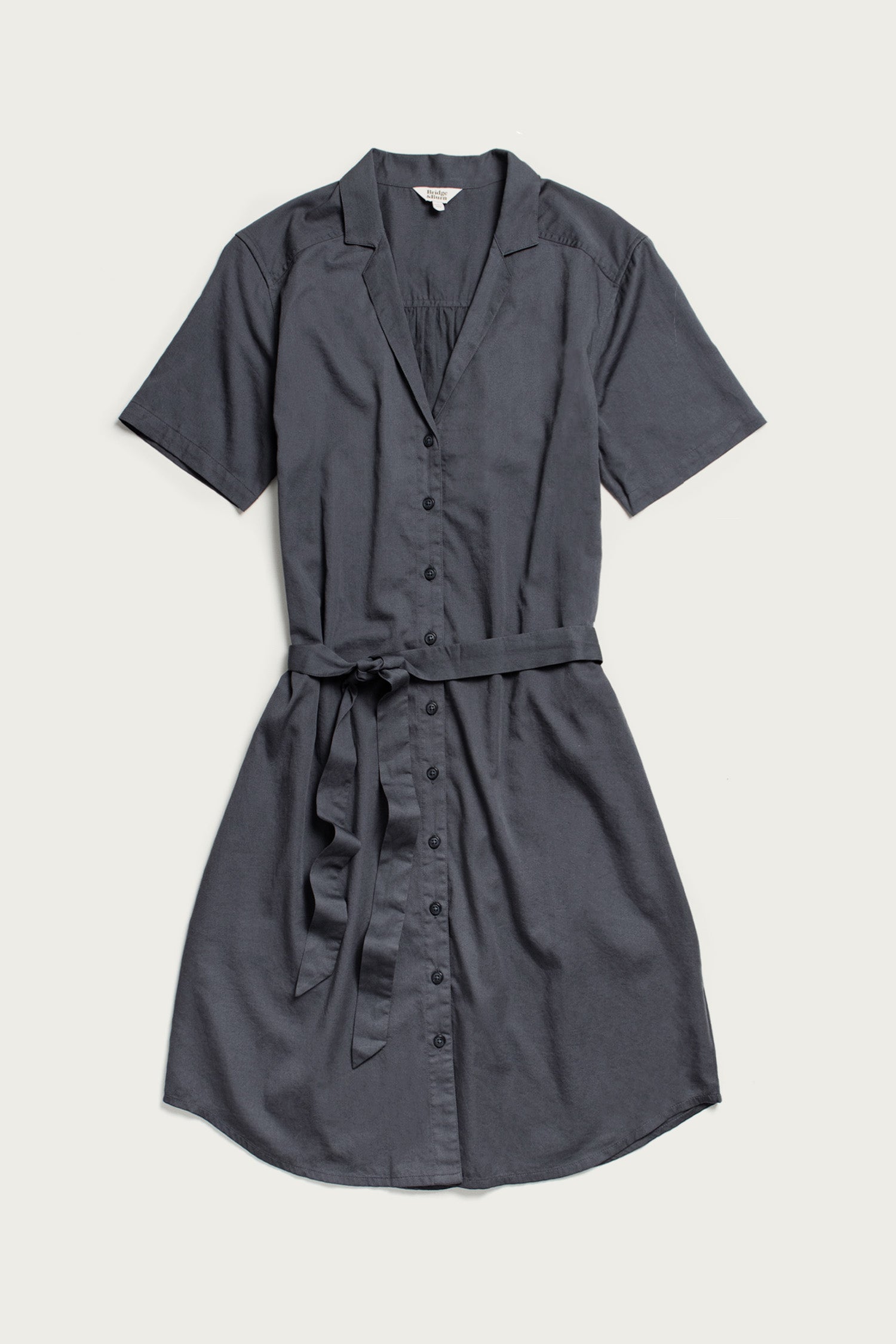 The Bridge & Burn Sofia Shirt Dress in light navy features short sleeves, a button front, a collar, and a matching fabric belt, shown laid flat on a light background.