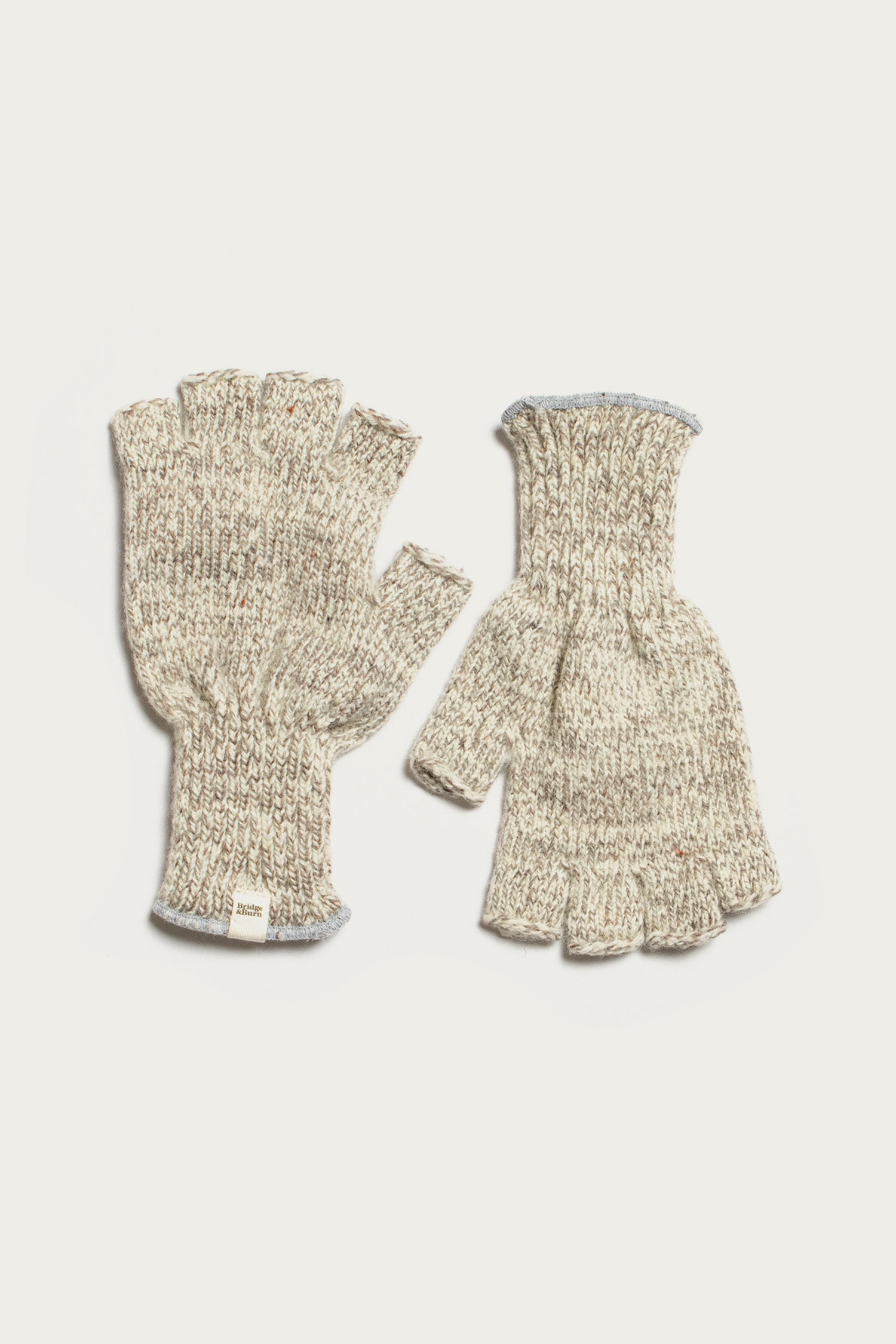 The Ragg Wool Fingerless Glove in Oatmeal by Bridge & Burn, shown flat on a white background—one glove displays the palm, the other the back. Both feature ribbed cuffs and a soft wool knit construction.