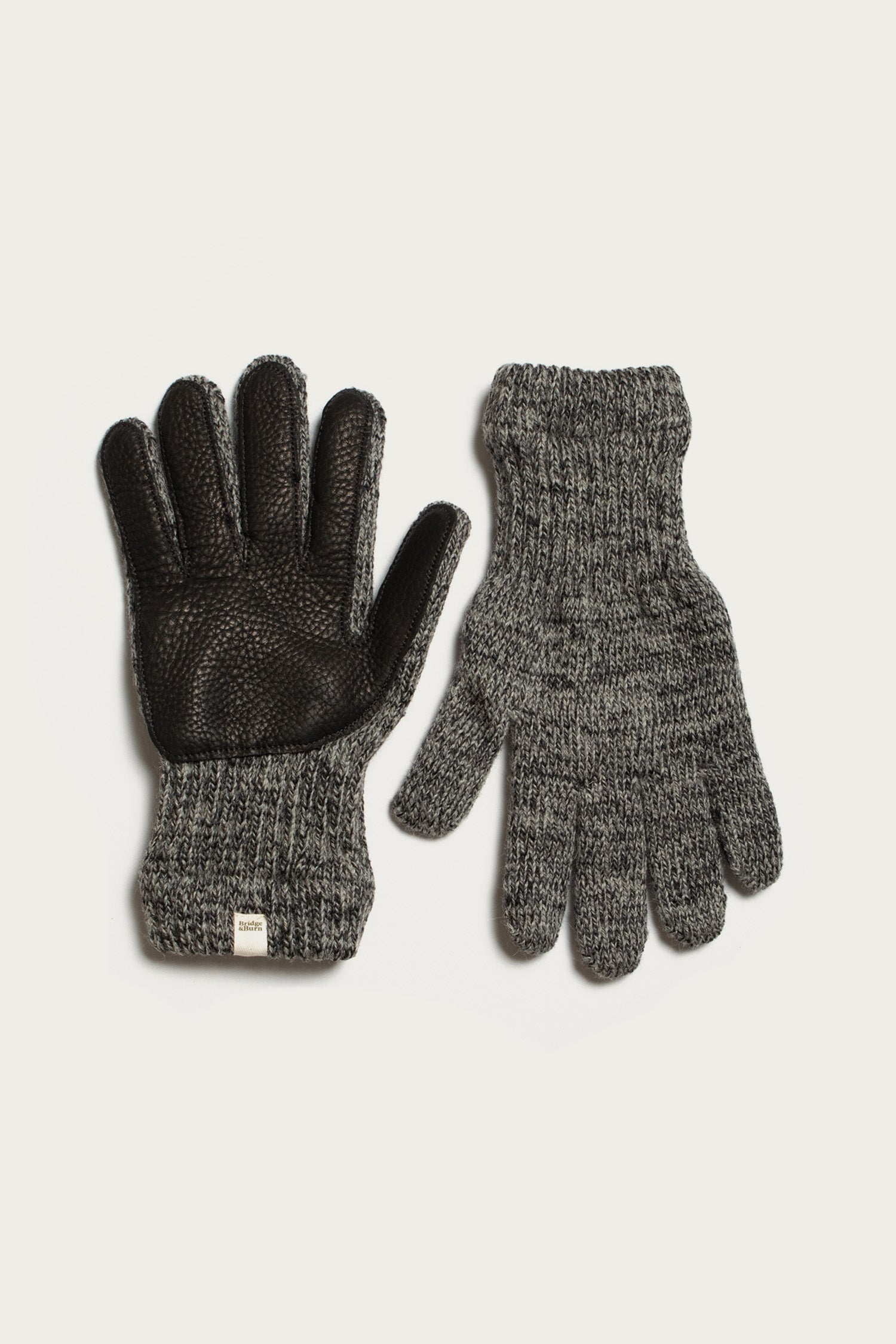 The Bridge & Burn Ragg Wool Lined Glove in Charcoal—made in the USA—features a textured black grip and small white tag on one glove, shown palm up, with the other displayed palm down on a white background.