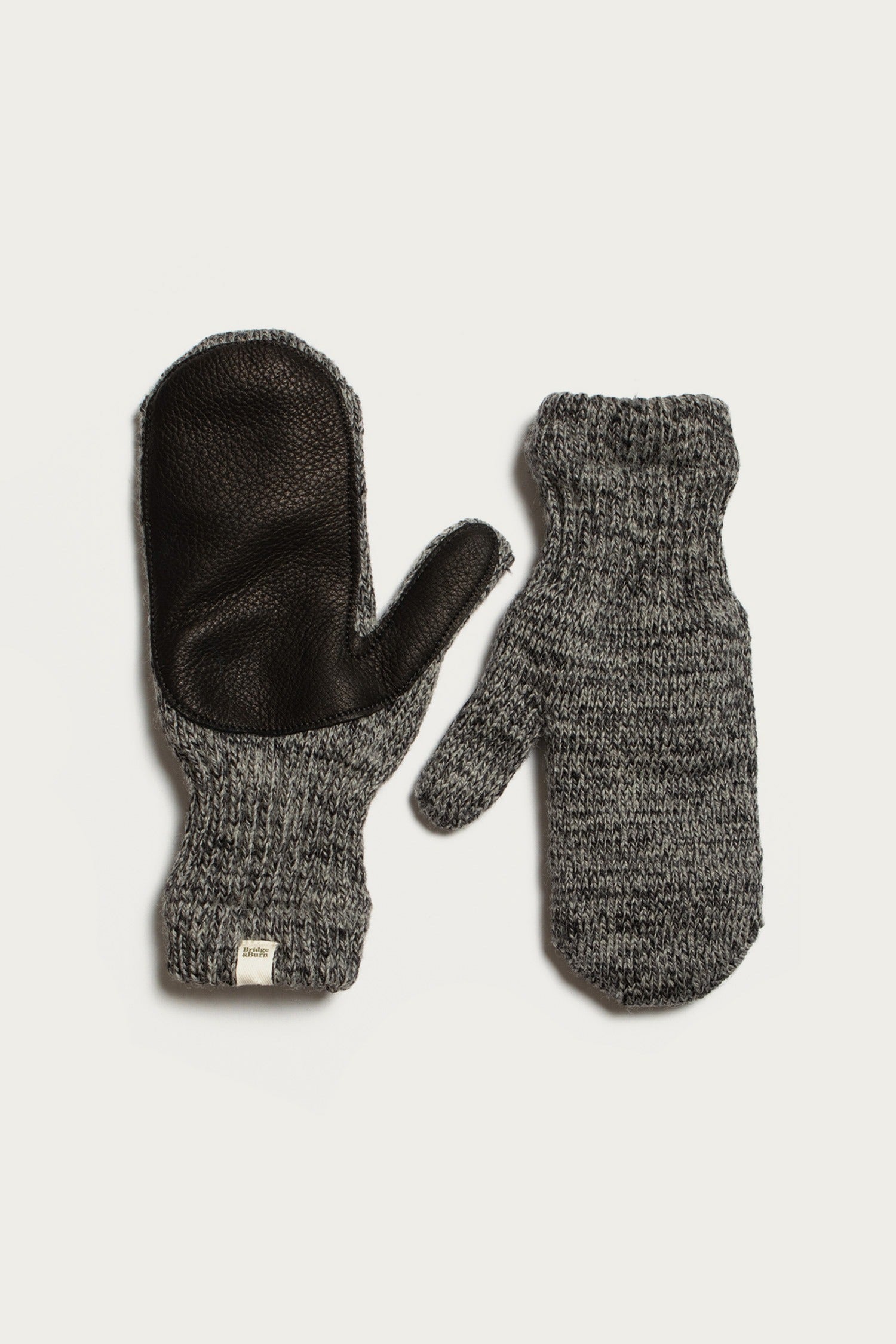 Bridge & Burn’s Ragg Wool Lined Mitten in Charcoal, made in the USA, features a black leather palm on one mitten and a knit textured back on the other, finished with ribbed cuffs for comfort.