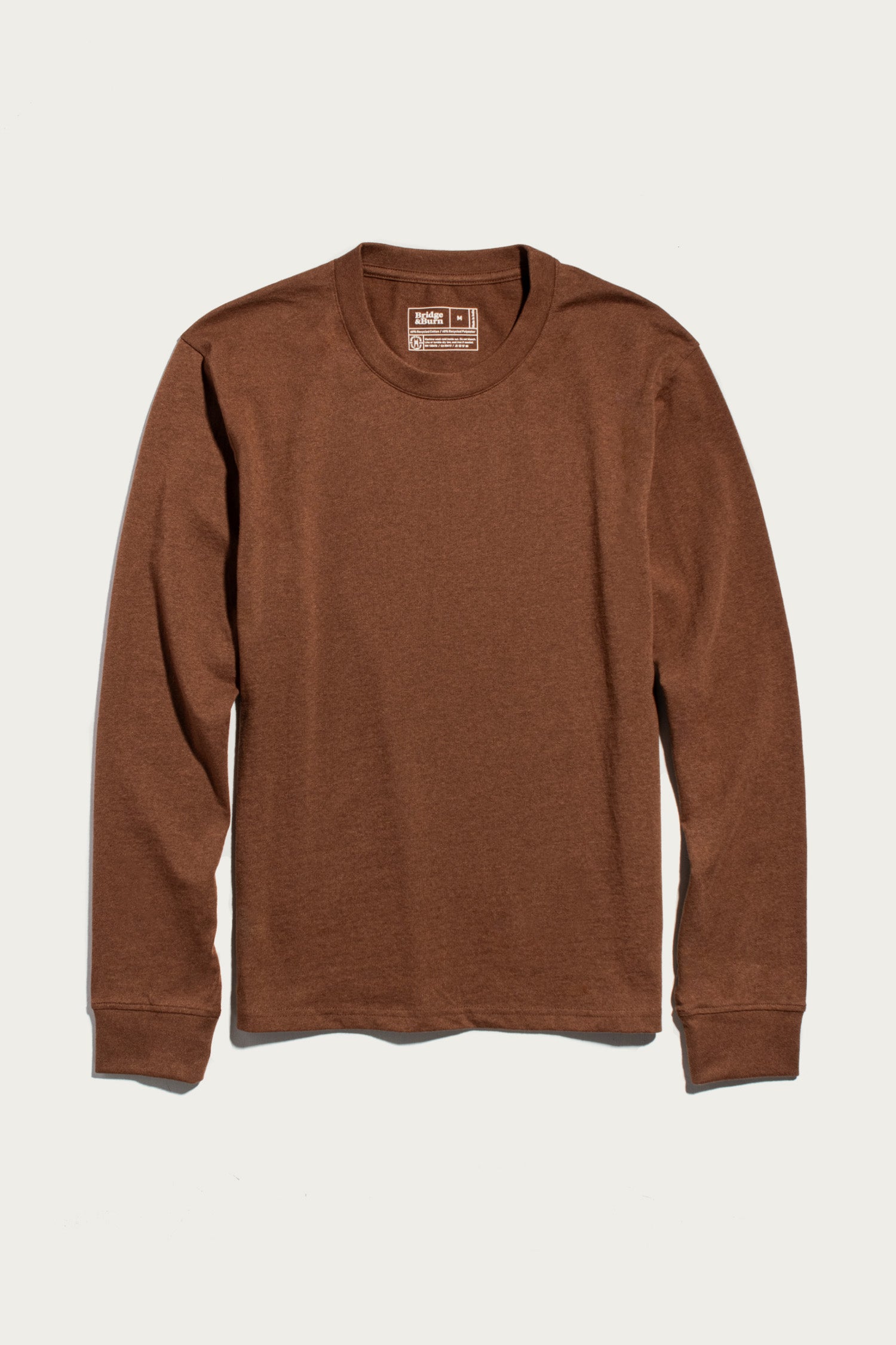 A relaxed fit, the Barney Long Sleeve Tee in Bronze by Bridge & Burn is laid flat on a white background. Crafted from soft recycled cotton, this plain crew neck shirt offers comfortable everyday wear.