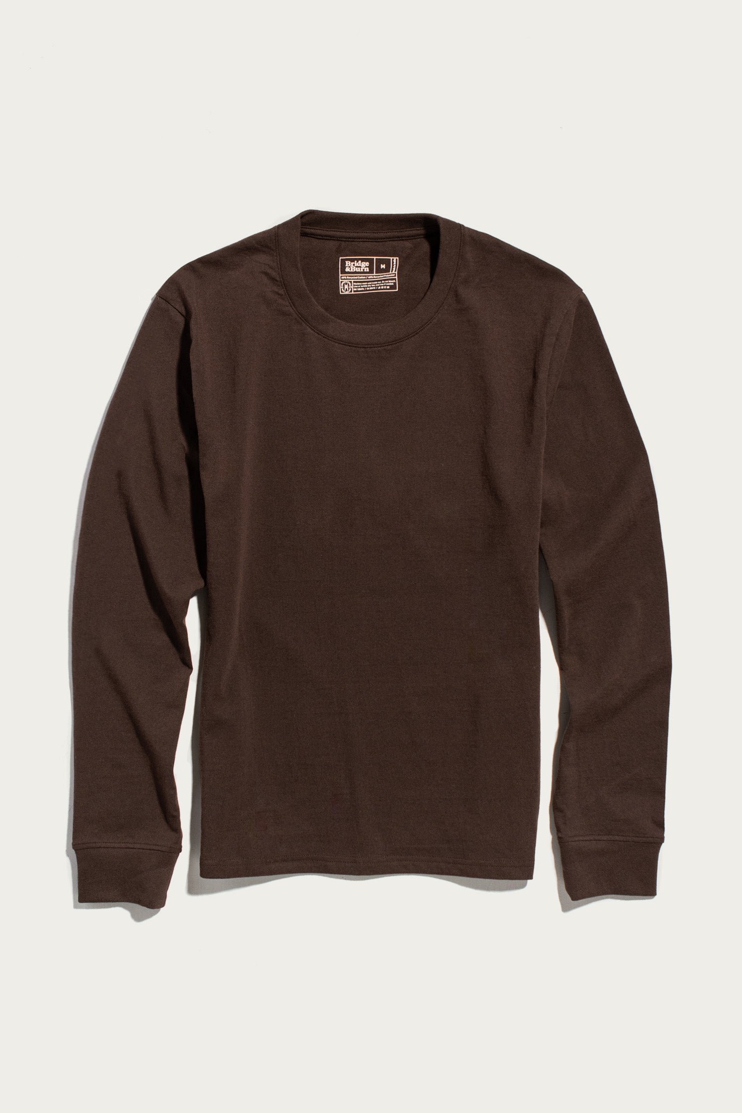 The Barney Long Sleeve Tee in Truffle by Bridge & Burn, a relaxed fit crew neck T-shirt made from recycled cotton, is shown laid flat on a white background.