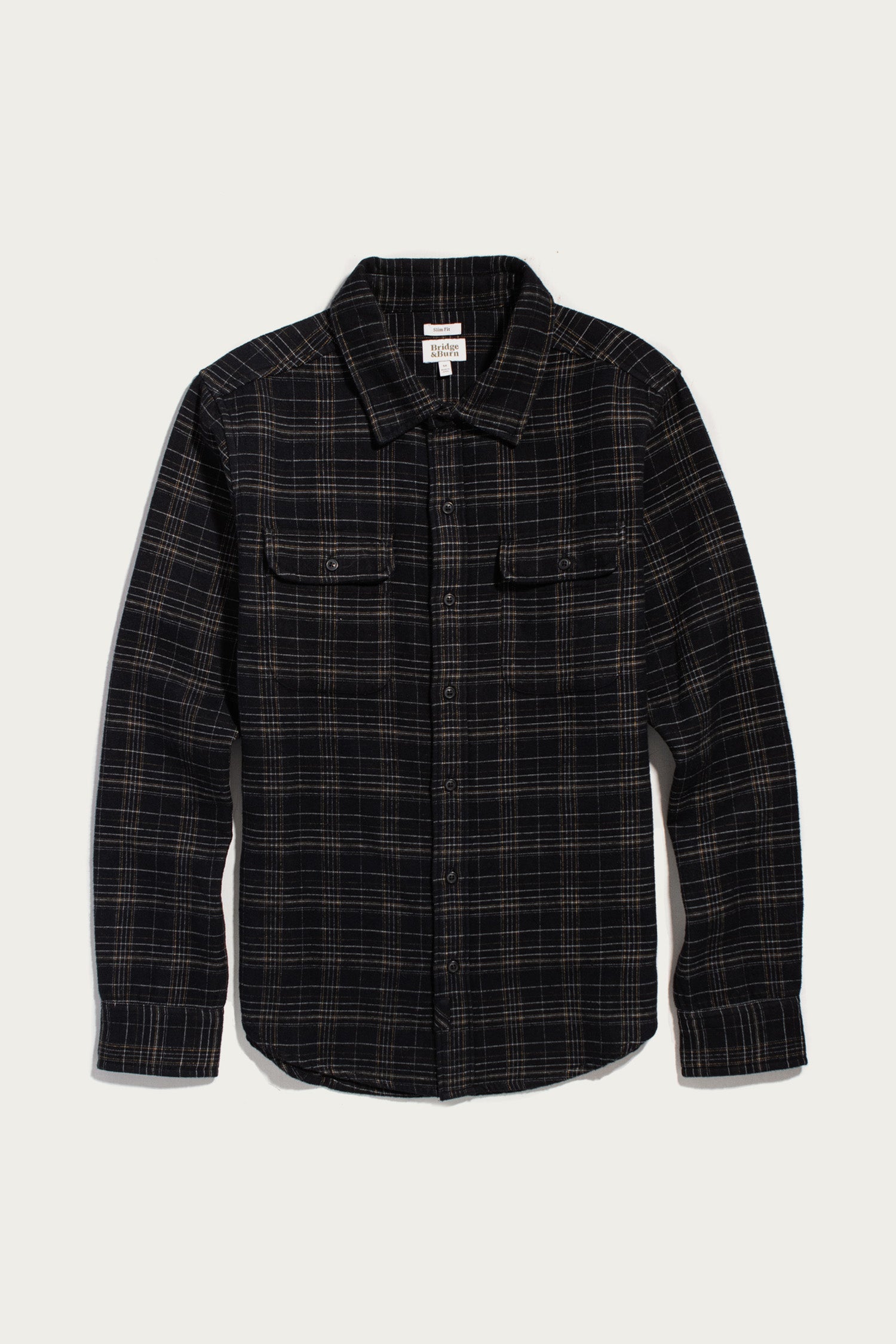Bridge & Burn Cole Slim Shirt in Obsidian Grid, a slim-fit long-sleeve black flannel featuring a tan grid pattern, two chest pockets, and a button-down front.