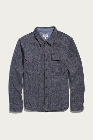 The Bridge & Burn Pointer Overshirt in Ocean Marl—a long-sleeve, button-up blue tweed twill overshirt with two chest pockets and brown buttons—is laid flat on a white background.