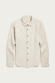 The Bridge & Burn Sutton Slim Shirt in Fawn Flannel is a slim-fit, long-sleeve shirt crafted from cream-colored organic cotton with a soft flannel texture. It features a single chest pocket, dark buttons, and is showcased on a plain white background for a clean, minimalist look.