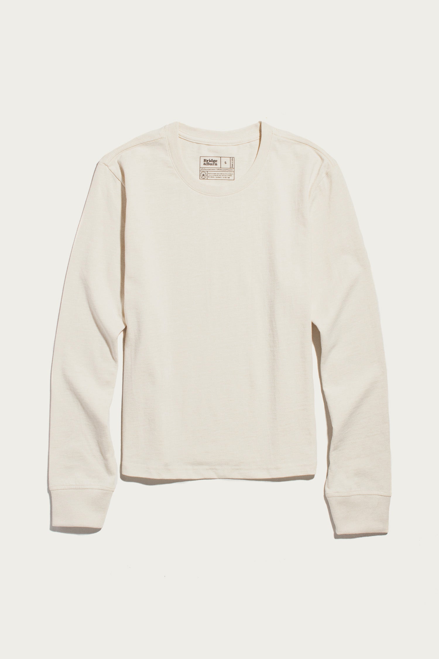 An ivory Audrey Long Sleeve Tee by Bridge & Burn, featuring a relaxed fit and crafted from soft recycled cotton, is laid flat on a white background.