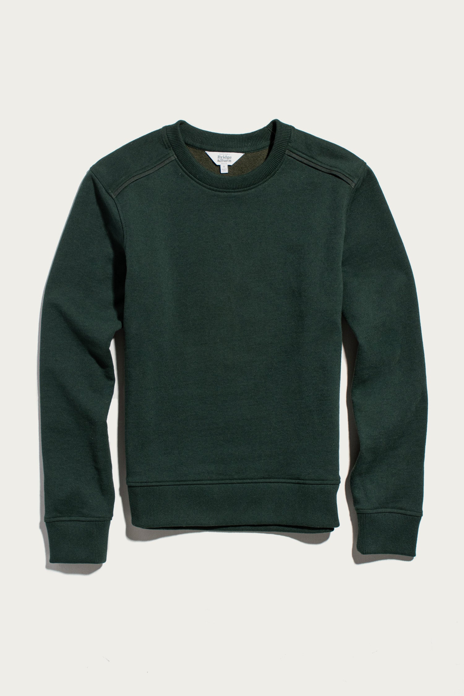 The Bridge & Burn Bailey Crew Sweatshirt in Juniper is a sustainable crewneck with long sleeves, ribbed cuffs, and waistband, shown laid flat on a light background.