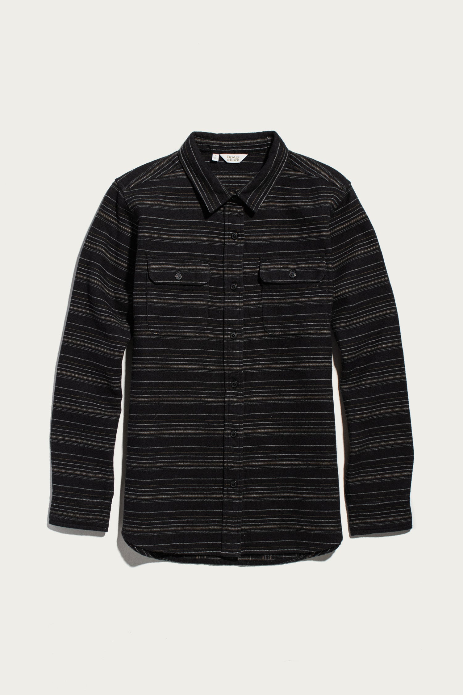Bridge & Burn Lenon Shirt / Raven Stripe, a relaxed fit over-shirt in black with thin horizontal grey stripes, featuring a collar and two chest pockets with button flaps.