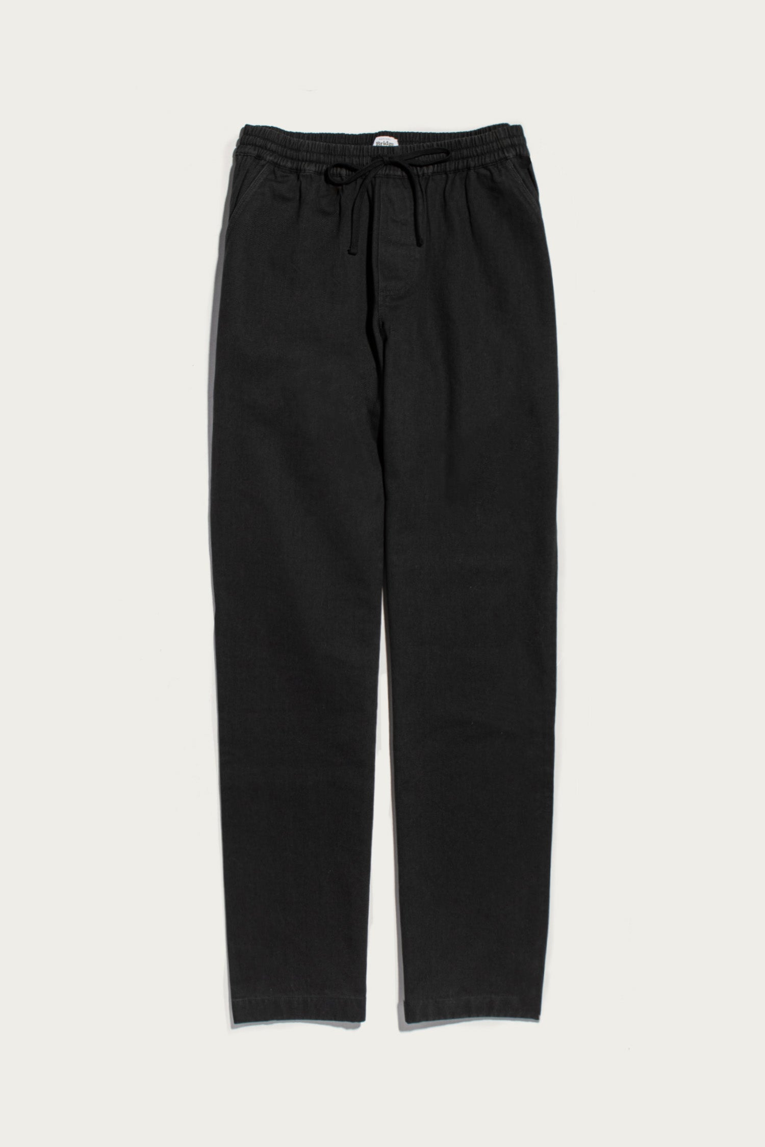 The Bridge & Burn Hayes Pant in Soft Black is a relaxed-fit, organic cotton pair with an elastic waistband and drawstring, shown against a plain white background.