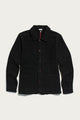 The Men’s Studio Chore Coat in Washed Black by Bridge & Burn, featuring a chore coat-style button-up design with a collar and three front pockets, is laid flat on a white background.