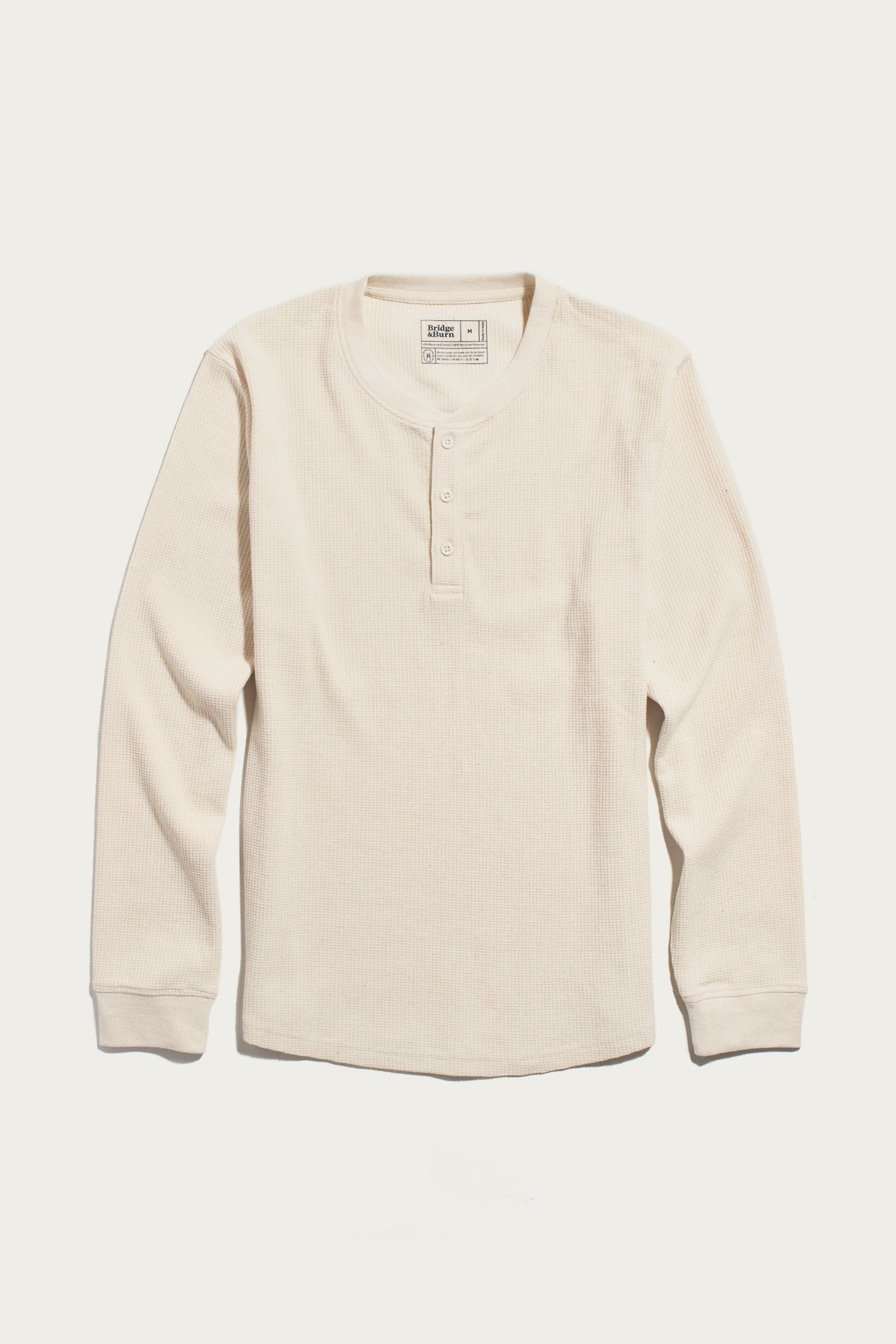 The Bridge & Burn Men’s Recycled Waffle Henley in Ivory—a long-sleeve, cream-colored shirt featuring a classic waffle-knit texture and three-button placket—is designed for effortless thermal layering and is shown laid flat on a white background.