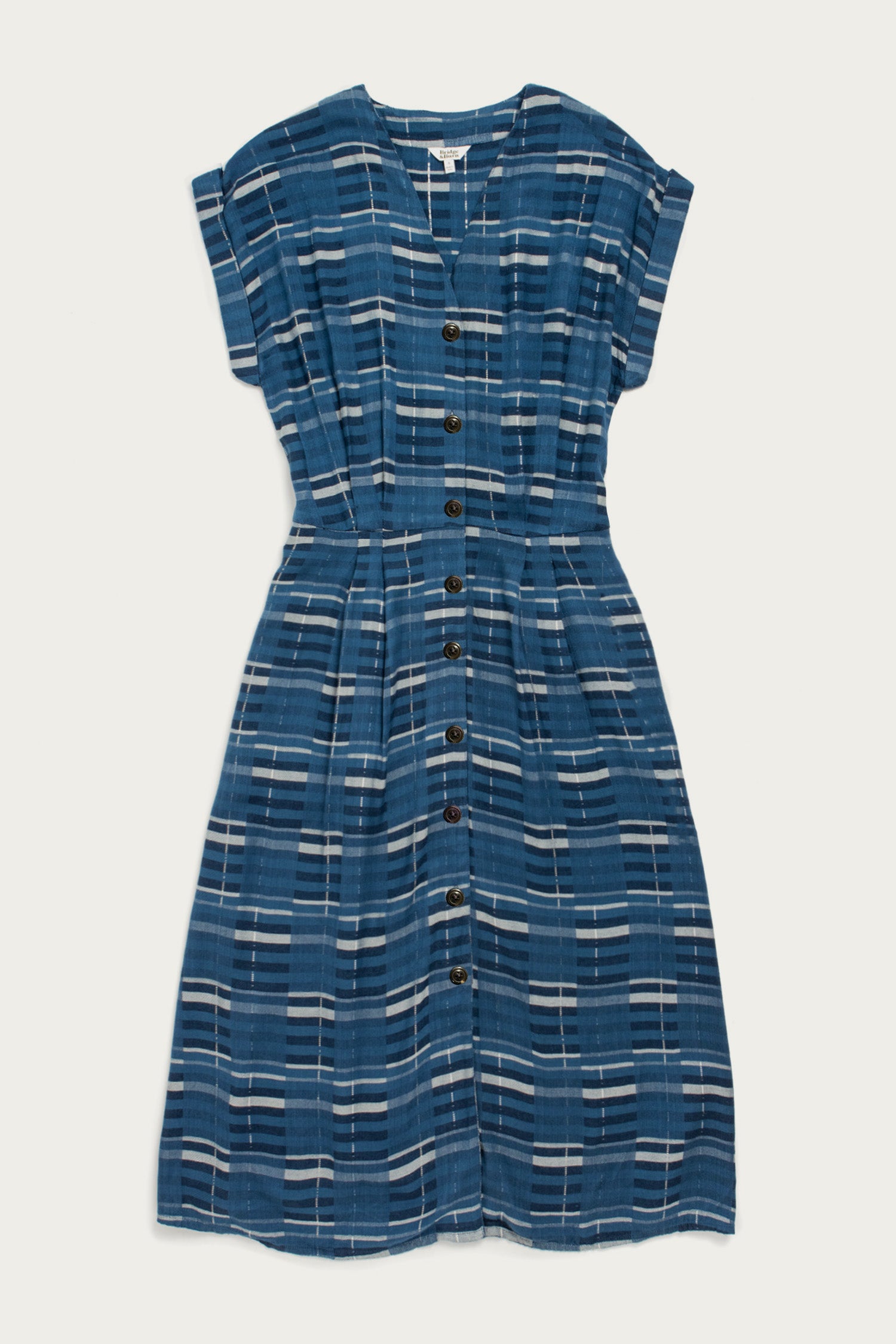 The Eileen Dress in Stormcrest Stripe by Bridge & Burn features blue, white, and gray stripes, a V-neck with front buttons, gathered waist, and A-line fit for a relaxed yet stylish midi-length look.