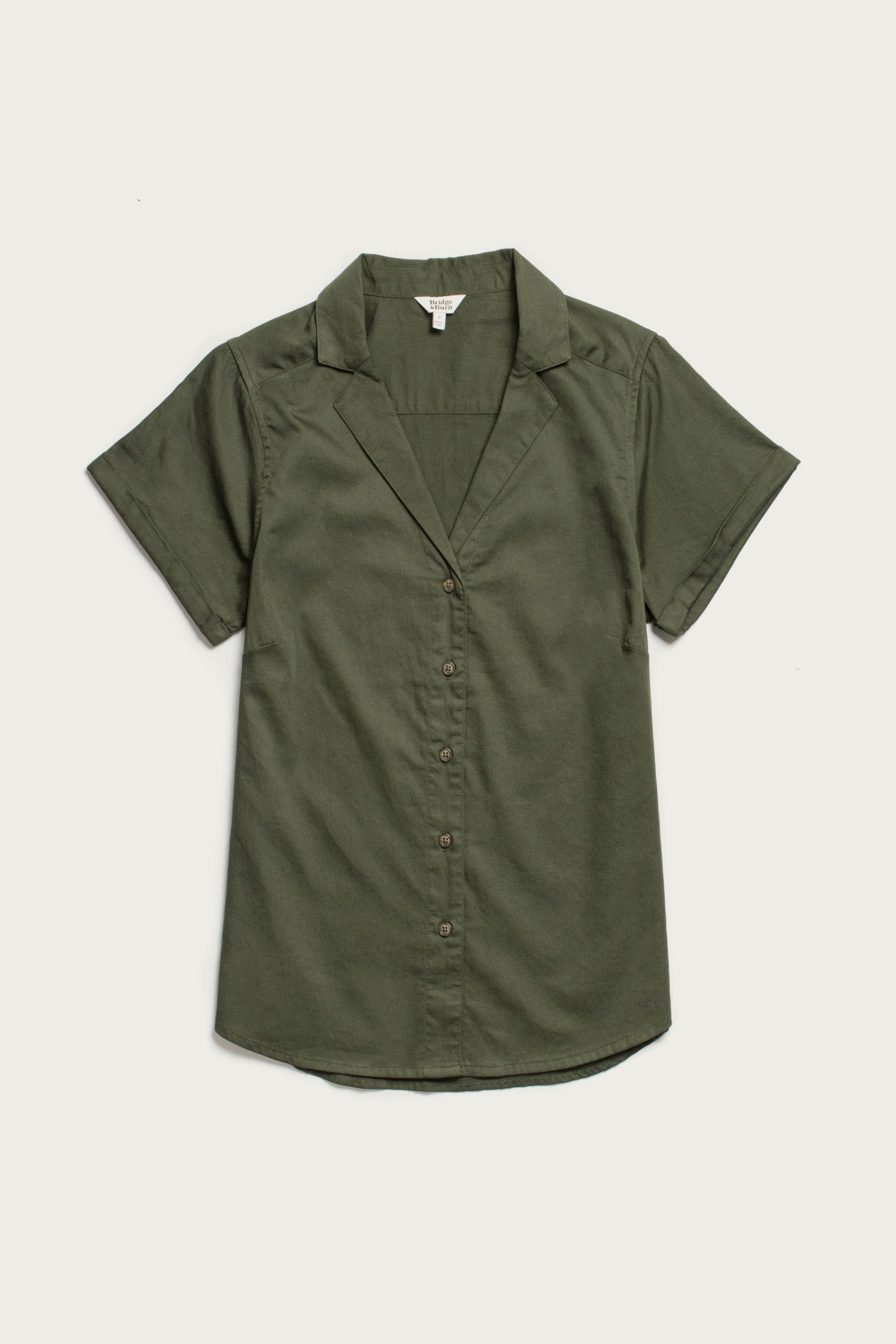 The Bridge & Burn Innes Shirt in Olive is a relaxed fit, short-sleeved, organic cotton button-up with a notched collar, shown laid flat on a white background.