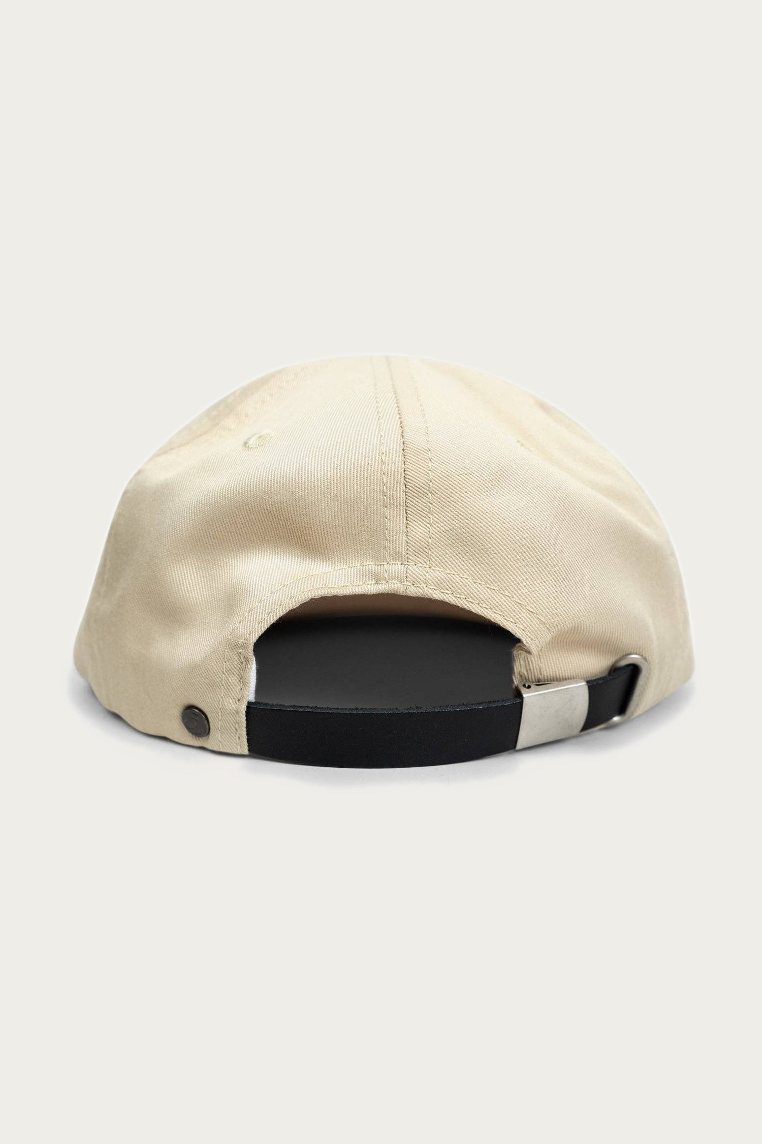 The Iron & Resin - Good Luck Hat in tan, made of cotton twill, is shown from the back with a black adjustable strap and metal buckle for size adjustment. The cap is set against a light, neutral background.