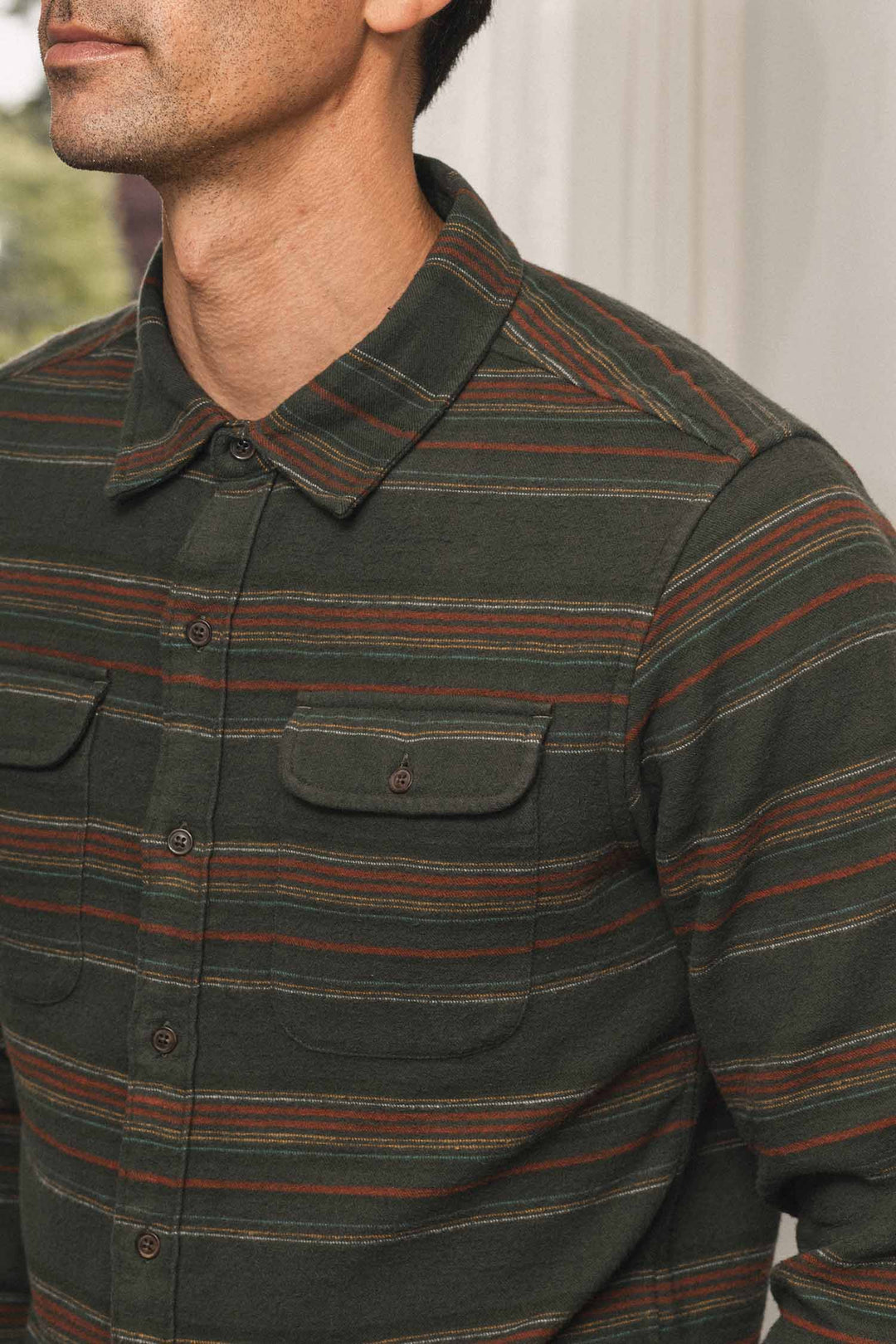 A dark green Cole Slim Shirt / Mallard Stripe button-down with thin horizontal stripes in red, yellow, and blue.