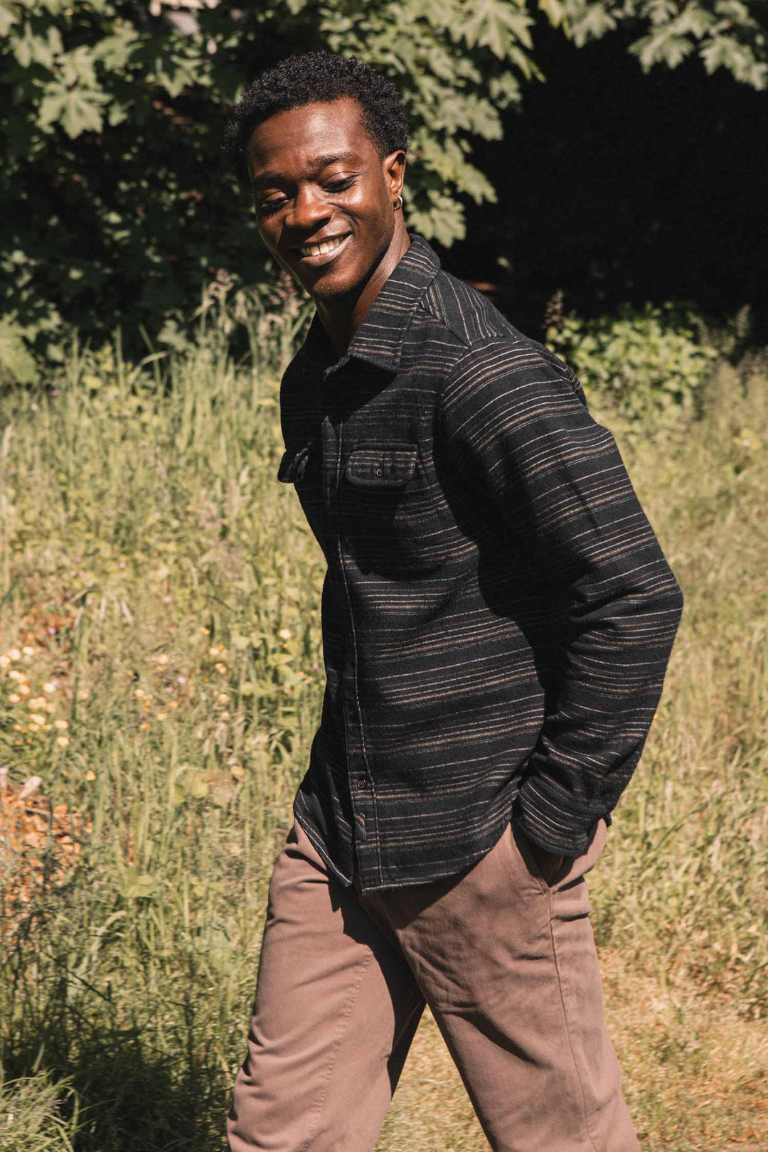 A smiling man wearing a Bridge & Burn Cole Slim Shirt / Raven Stripe, a slim-fit, long-sleeved, black button-down shirt with horizontal stripes.