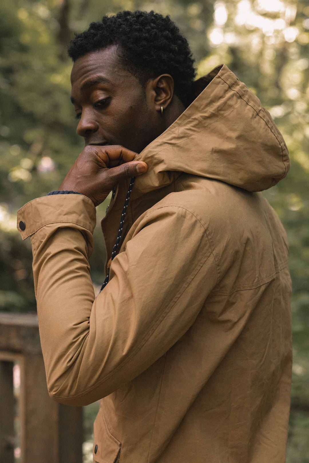 A person wearing a tan Bridge & Burn Marshall Jacket / Dark Khaki Waxed Canvas with their hand held to their chin.