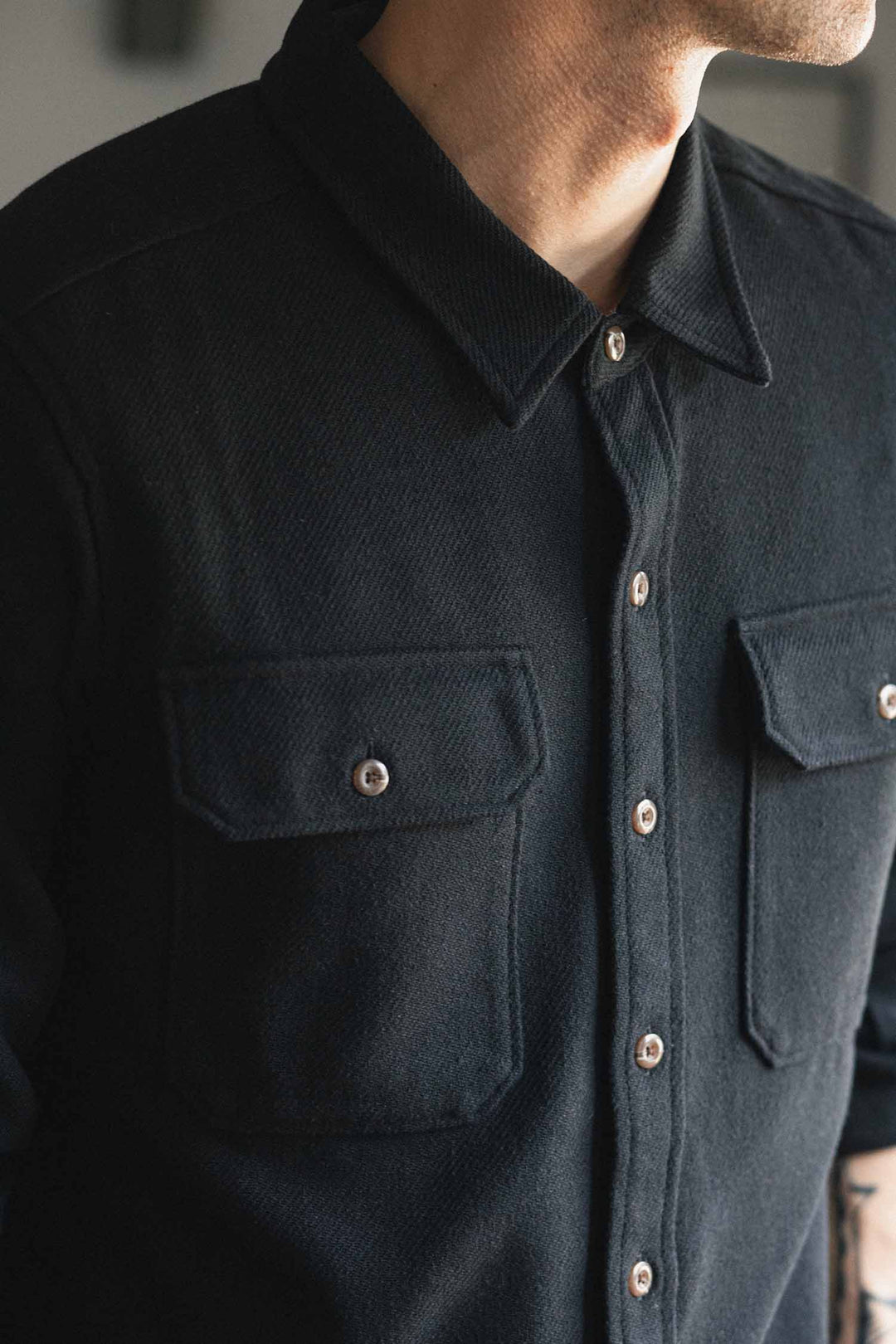 A person wearing the Bridge & Burn Pointer Overshirt in Ink Stone, featuring two chest pockets, is shown from the shoulders to mid-torso with their face mostly out of frame.