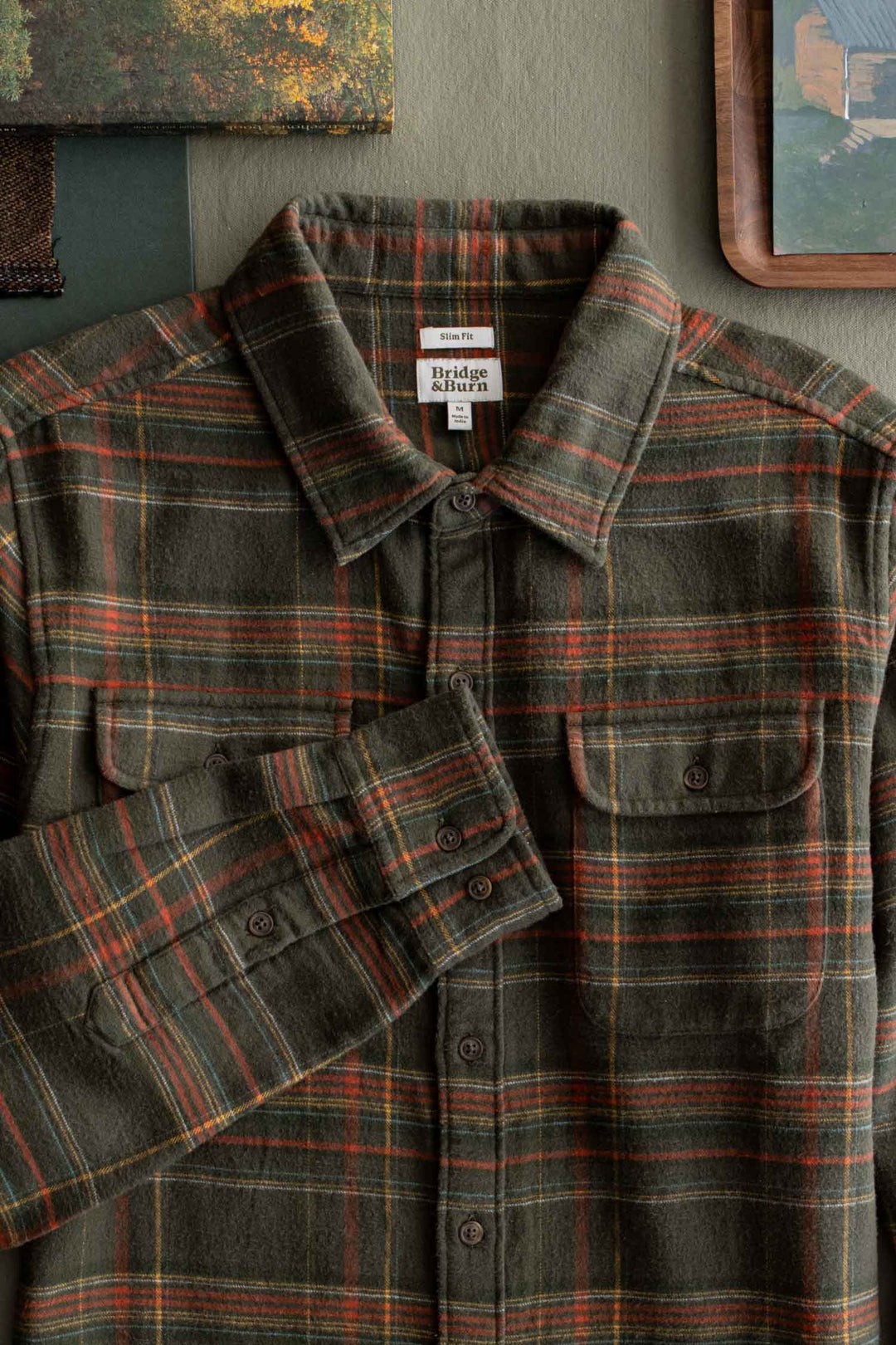 Bridge & Burn Cole Slim Shirt in Timberline Plaid, an olive green slim fit flannel with an orange and yellow pattern, long sleeves, and two button-flap chest pockets.