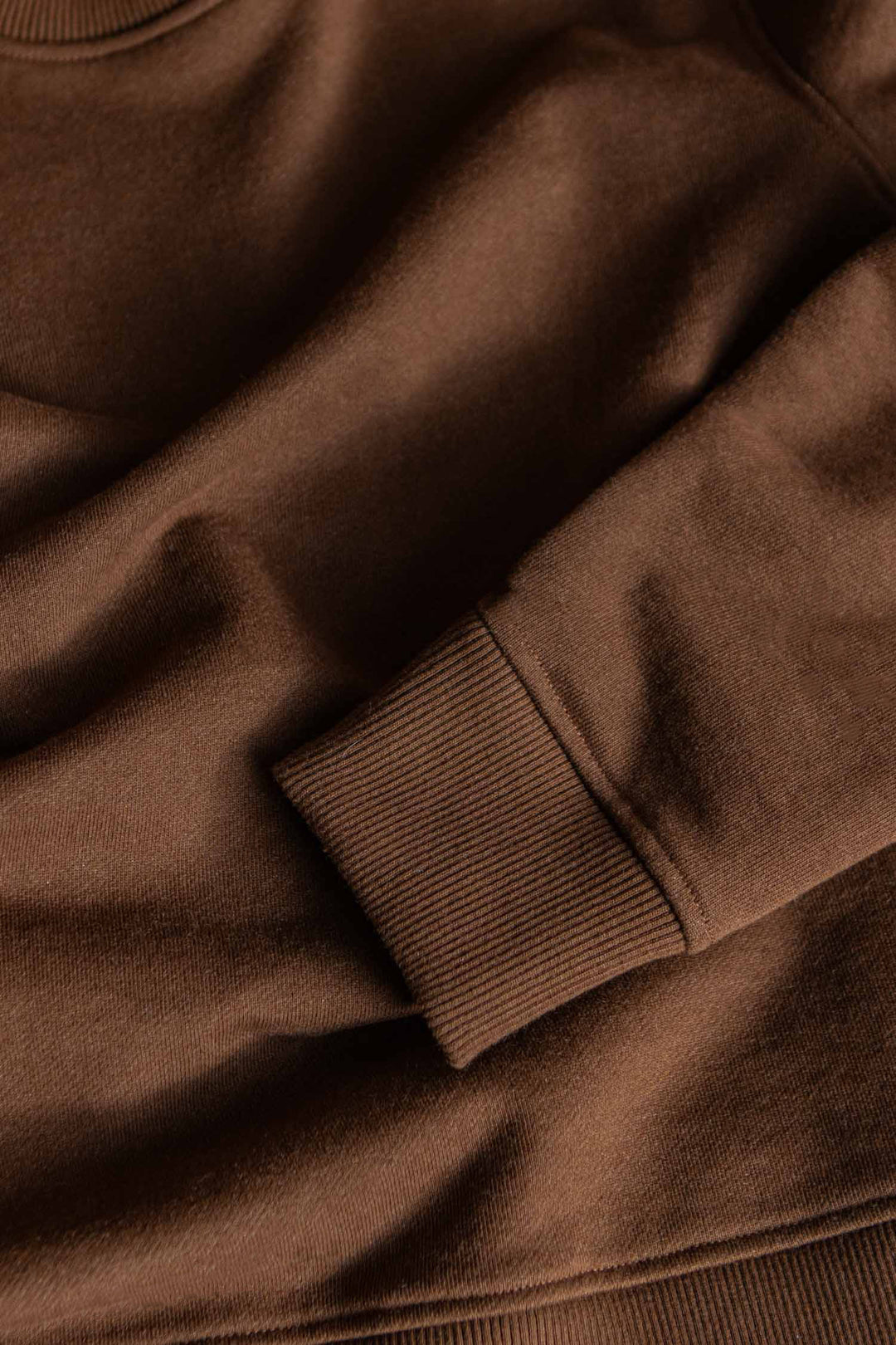 Close-up of the Bridge & Burn Mason Hoodie in Cumin, showcasing the long sleeve with ribbed cuff and highlighting the soft, recycled French terry fabric texture.