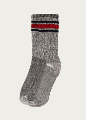 The American Trench - Merino Activity Crew in Grey showcases a pair of crew socks with a subtle metallic sheen, expertly crafted from moisture-wicking Merino wool for day-long comfort. These anti-bacterial socks feature two horizontal stripes—one red and one black—near the top, and are presented against a simple light background.
